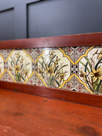 Antique pine washstand with decorative ceramic tile strip featuring yellow daffodils and wooden knobs in late victorian style