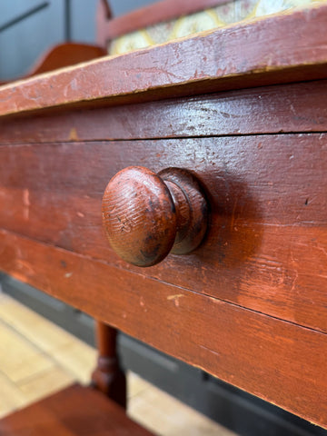 Worn reddish brown wooden knob on a late victorian pine washstand side table with textured surface