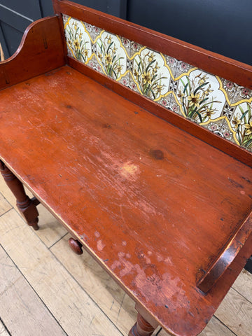Antique pine washstand with a late victorian rustic wooden bench and decorative floral tiles with wooden knobs