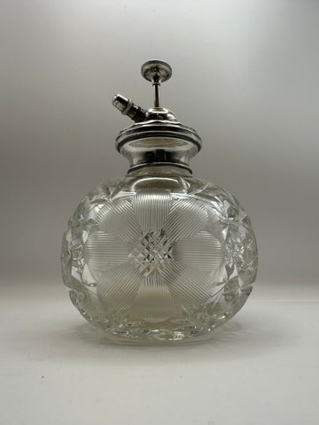 A clear cut glass perfume atomizer with an antique silver topped spray nozzle for dressing table use