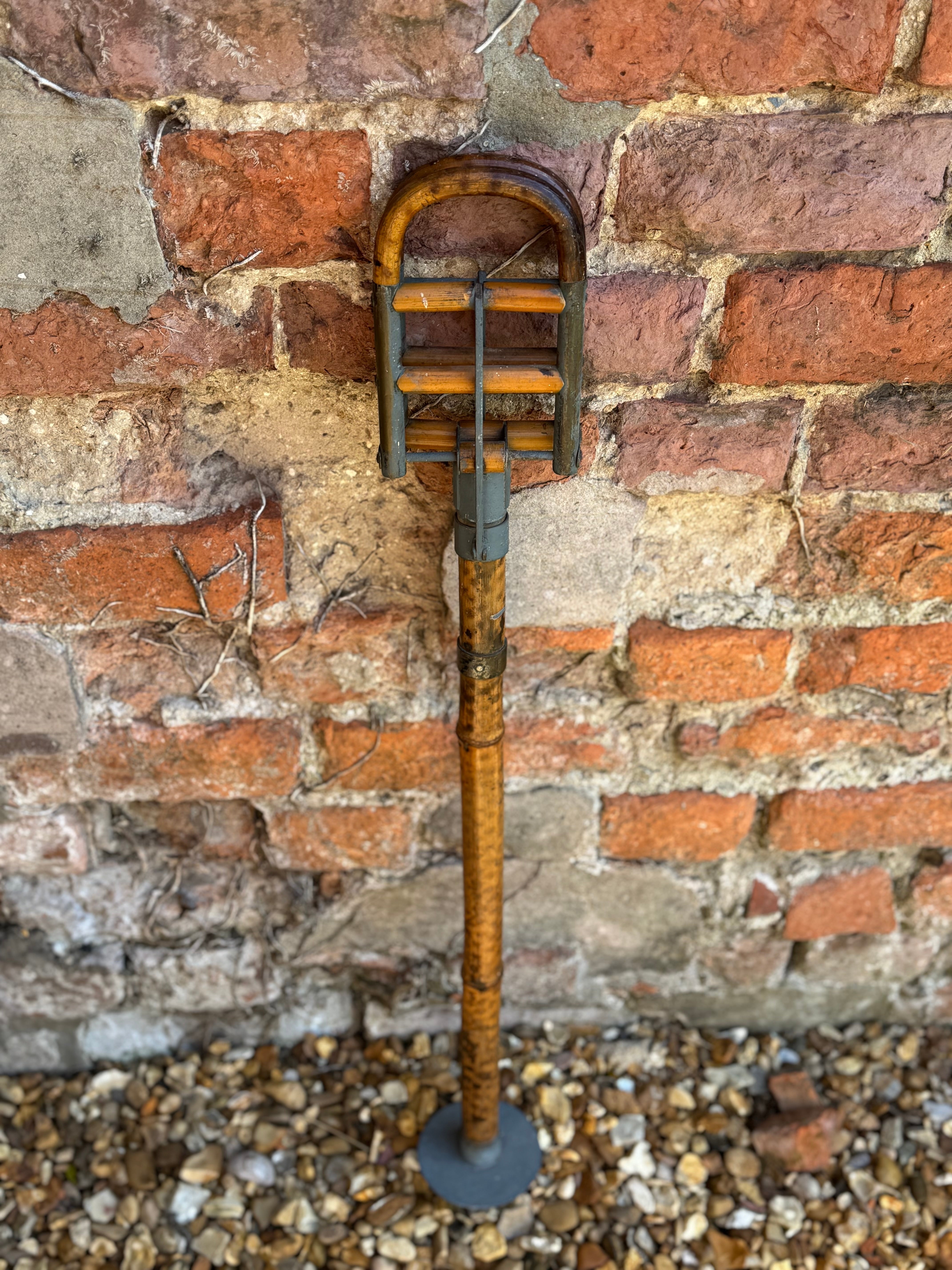Vintage wooden and metal cricket bat with curved handle and weathered finish in antique victorian bamboo shooting stick design