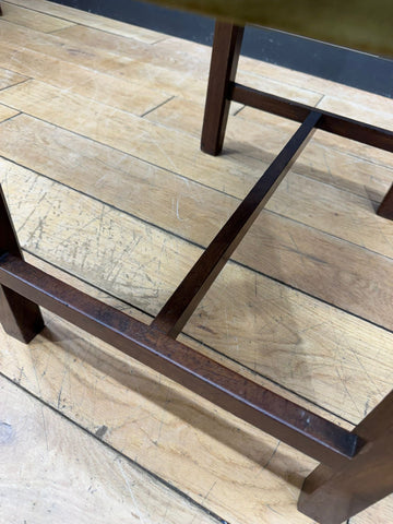Dark brown mahogany legs of an antique victorian upholstered stool with sturdy rectangular design and visible grain