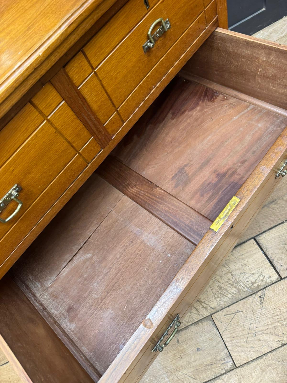 Antique walnut chest of drawers by maple and co with warm wood drawer fronts and brass handles showing dark wood interior