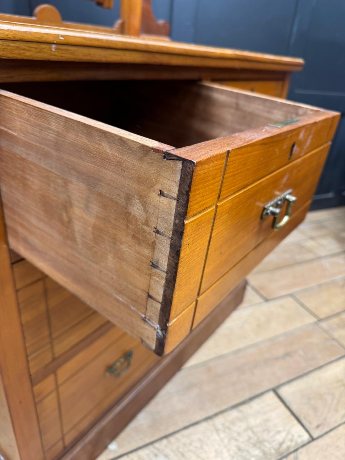 A polished golden brown antique walnut chest of drawers by maple and co with brass handle and visible drawer fronts