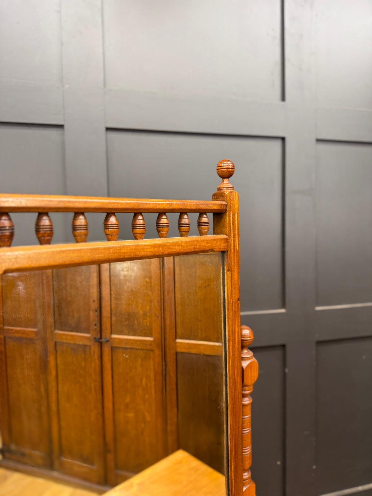 Antique walnut chest of drawers with oak-framed mirror and polished wooden border featuring decorative turned balusters and drawer fronts