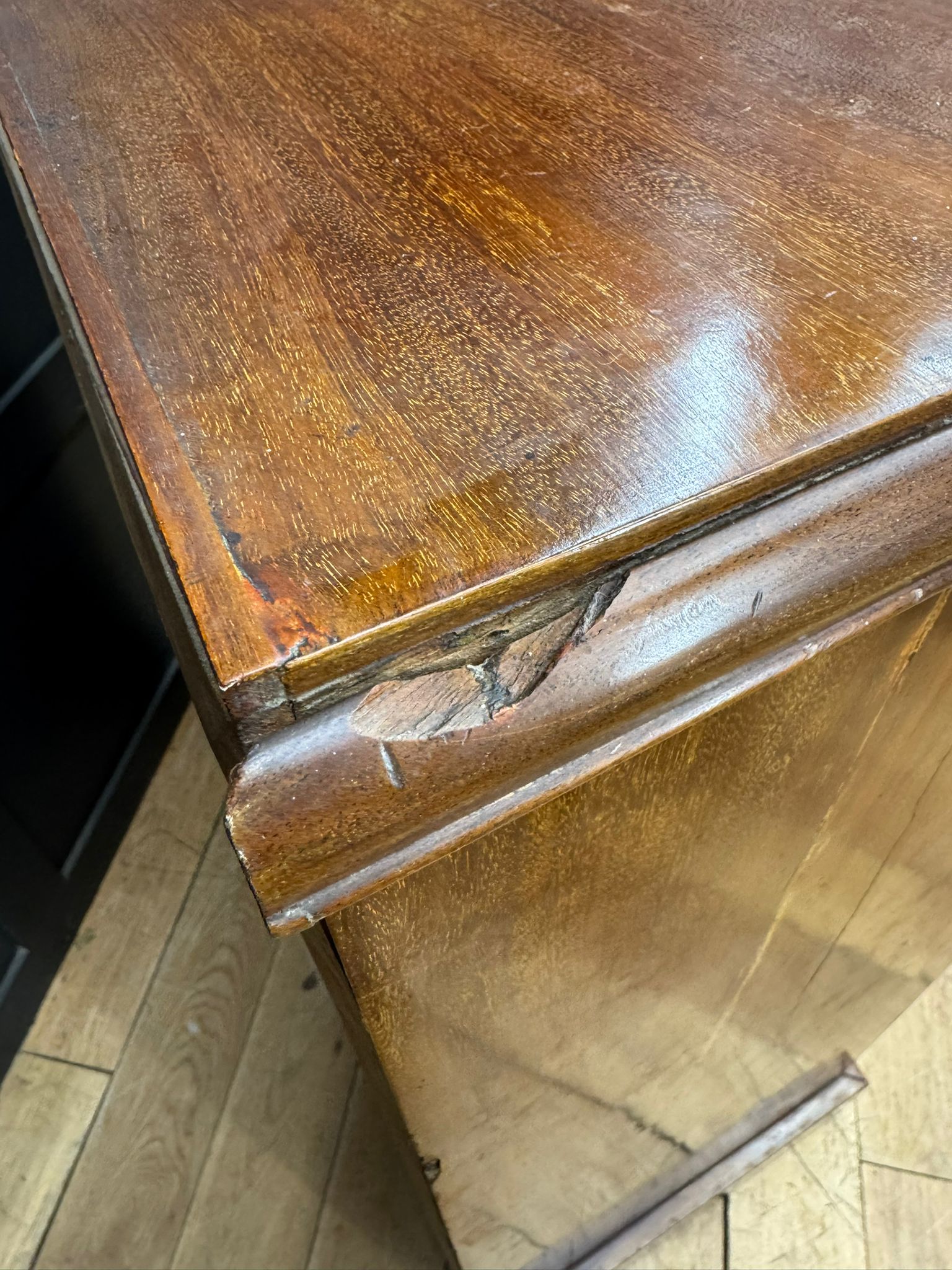 A polished dark brown antique walnut linen cabinet desk with visible wood grain and minor edge damage