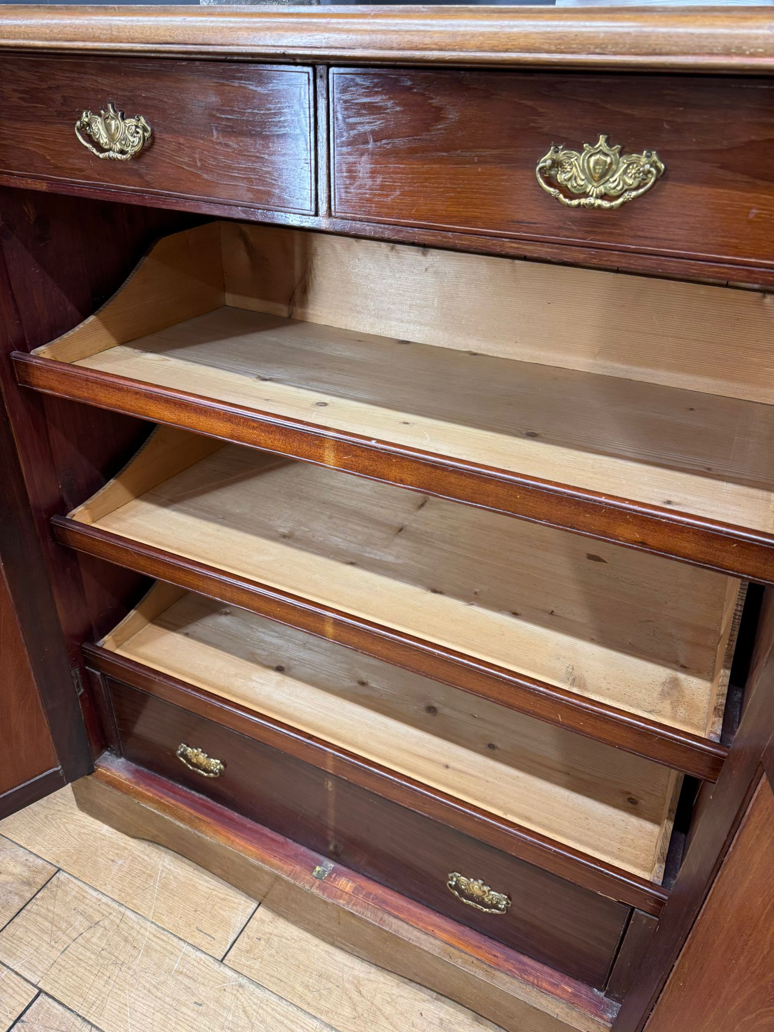 Antique walnut linen cabinet with dark brown finish wooden bookcase and ornate brass handles on drawers