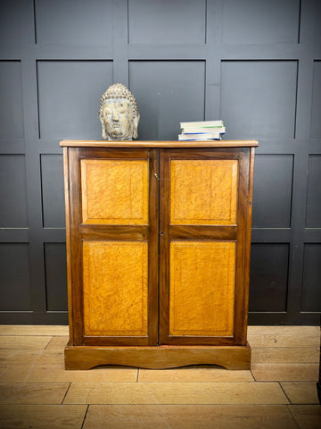 Antique walnut linen cabinet with two doors featuring warm golden brown veneer and dark wood framing for clothes storage