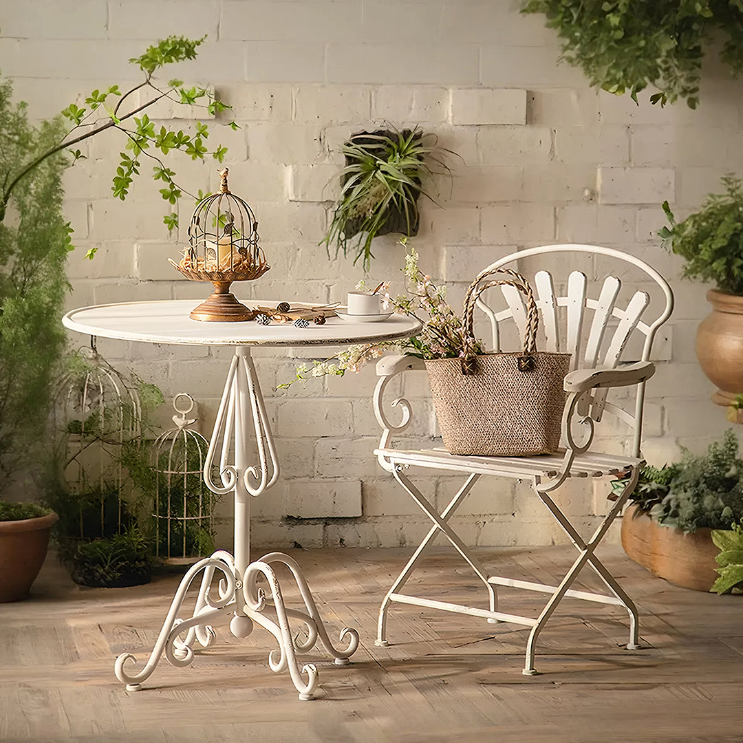 White wrought iron patio table with ornate scrollwork legs and round top in antonia outdoor garden dining table set
