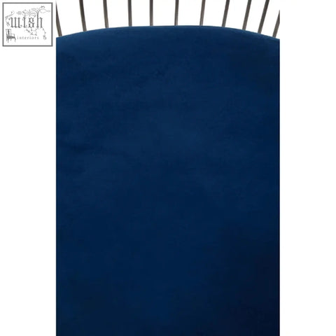 Deep navy blue plush-textured crib sheet with curved top edge complementing anzio navy blue velvet chair with brushed silver accents