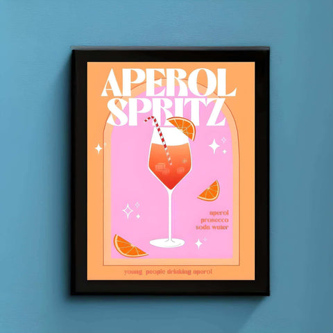 A vibrant pink and orange aperol spritz cocktail print in a black frame featuring a stylized spritz cocktail with orange garnish
