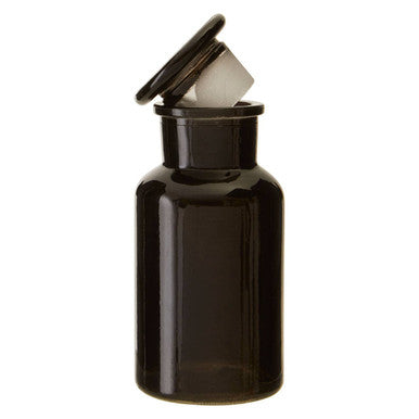 Black glass reagent apothecary bottle with black lid slightly open showing white contents inside