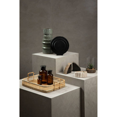 Woven wicker tray holding amber glass bottles and apothecary black glass reagent bottle for stylish storage