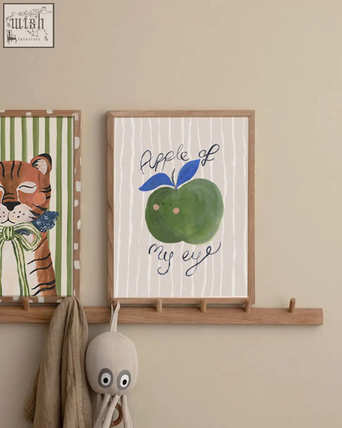 A framed hand painted apple artwork with a green apple blue leaves and apple of my eye text on white striped background