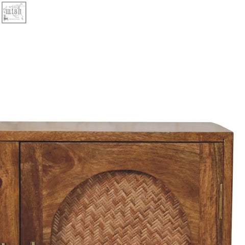 A rustic wooden sideboard with natural finish and arched woven rattan panels on two doors