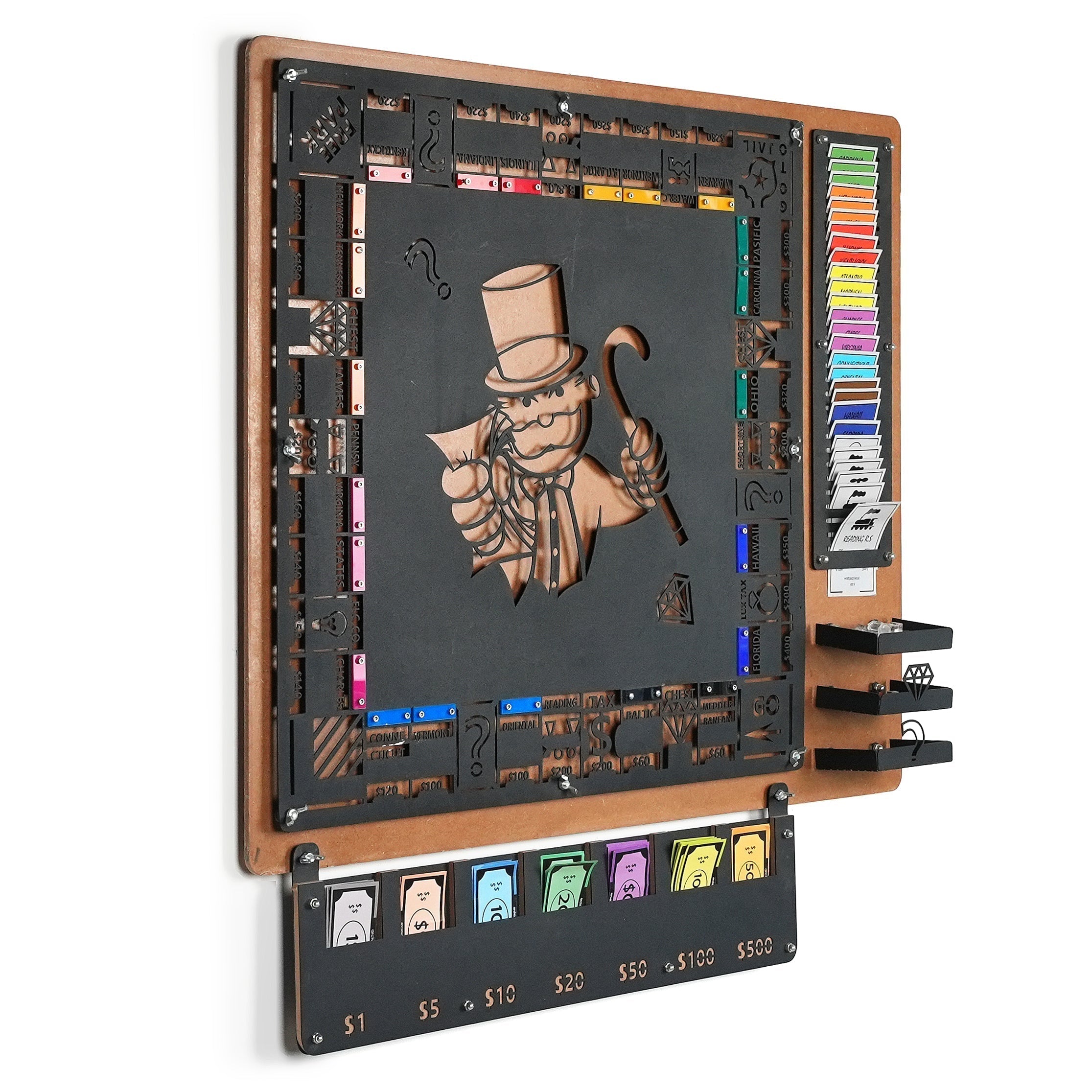 Black metal monopoly game board with laser-cut mr illustration and community chest cards on flat surface for all age range