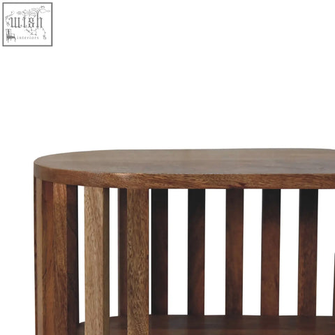 Dark brown wooden oval coffee table with vertical slat legs in mango wood featuring an oak-ish finish ariella chest style