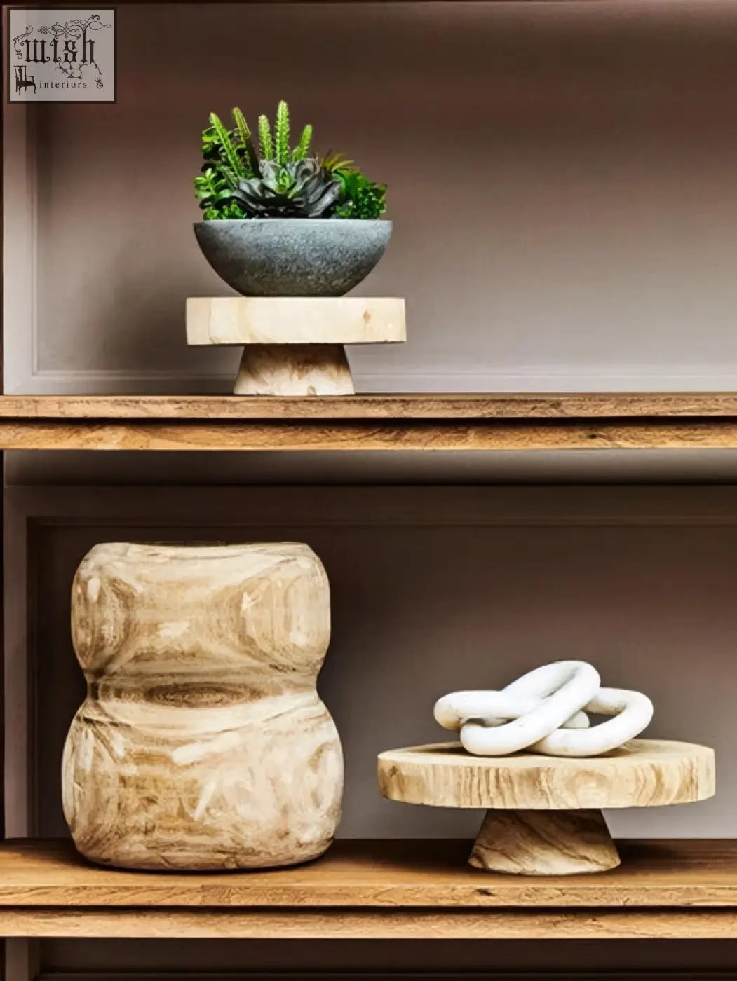 A light wooden pedestal holding a white ceramic ring sculpture next to an arlo natural engraved round bowl