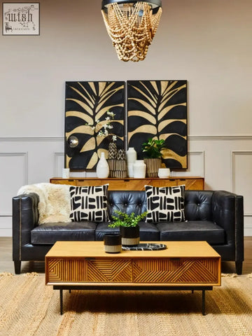 Black leather tufted sofa with geometric pillows next to a small engraved natural and black planter