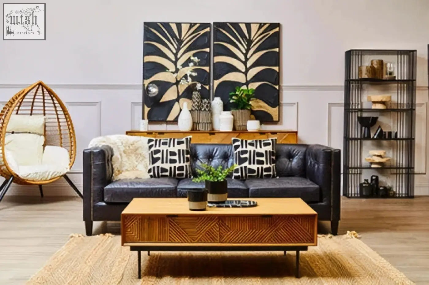 Dark blue leather sofa with black and white pillows next to a small engraved natural and black planter