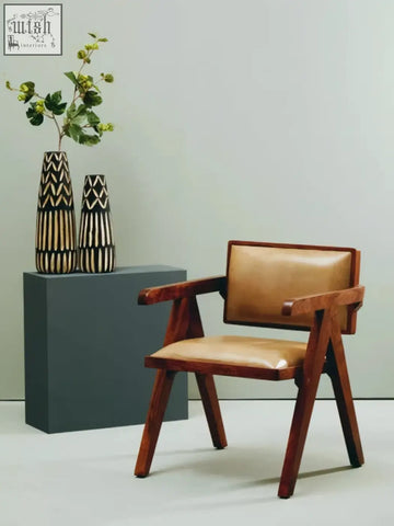Tan leather upholstered armchair with wooden frame shown next to a small engraved wooden vase perfect for decor