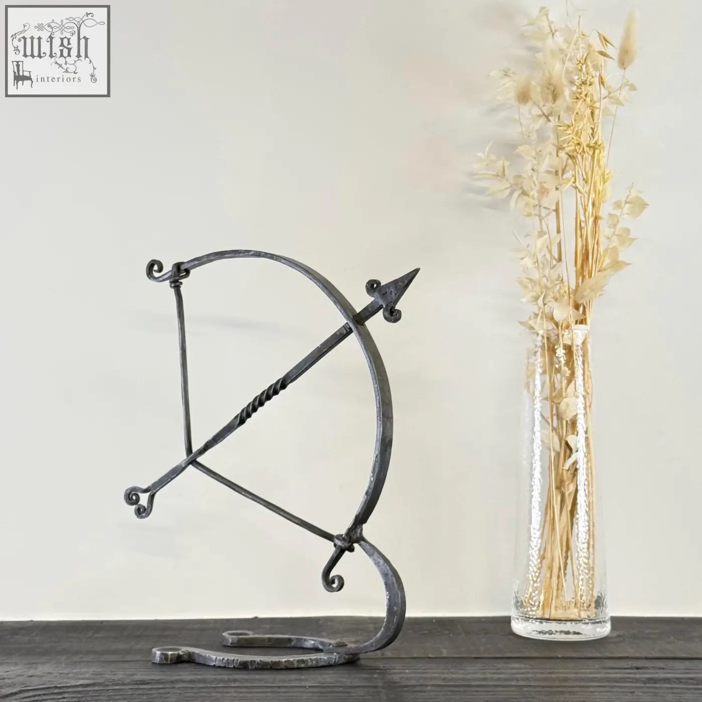 Black solid iron archer sculpture with hammer marks and ornate scrollwork in armillary arrow wrought iron design