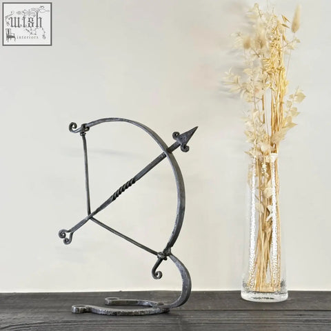 Black solid iron archer sculpture with hammer marks and ornate scrollwork in armillary arrow wrought iron design