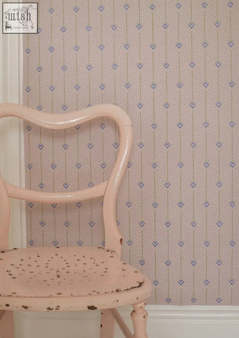 A vintage-style chair with a soft pink painted finish and ornate wood frame featured with arrows of love archive print wallpaper