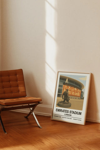 A framed poster print featuring a vintage-style orange-brown illustration of emirates stadium london with bold black text