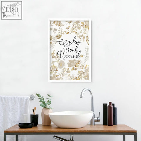 A wall art print with delicate soft gold floral pattern and relax soak unwind in black cursive for bathroom walls