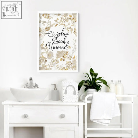 White framed wall art print with gold and cream floral design and black cursive relax soak unwind for bathroom walls