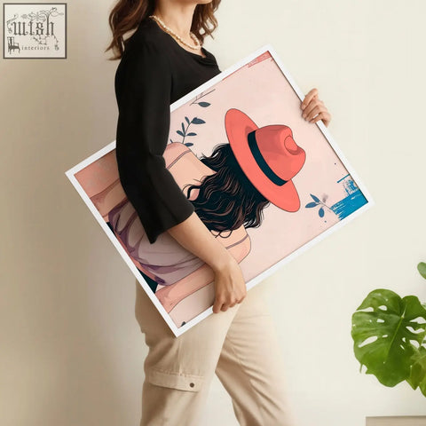 A framed boho women wall art print of a woman with dark hair and a coral hat on a soft pink background with leaves and butterflies