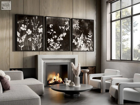Black and white mink botanical dark floral wall art prints in sleek black frames hanging on living room wall above fireplace