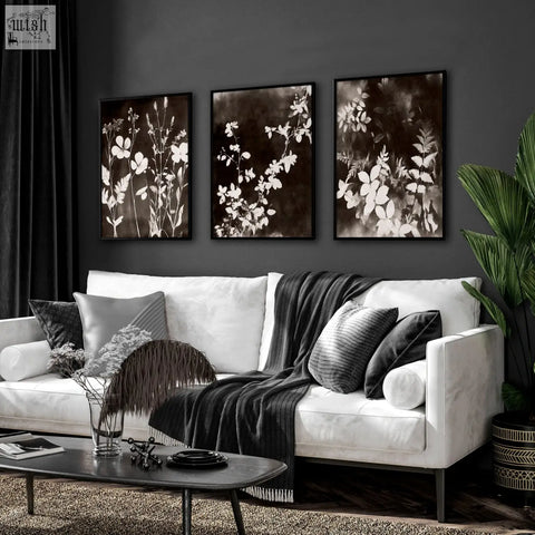 Three framed mink botanical dark floral wall art prints with white floral silhouettes hang on living room wall above sofa