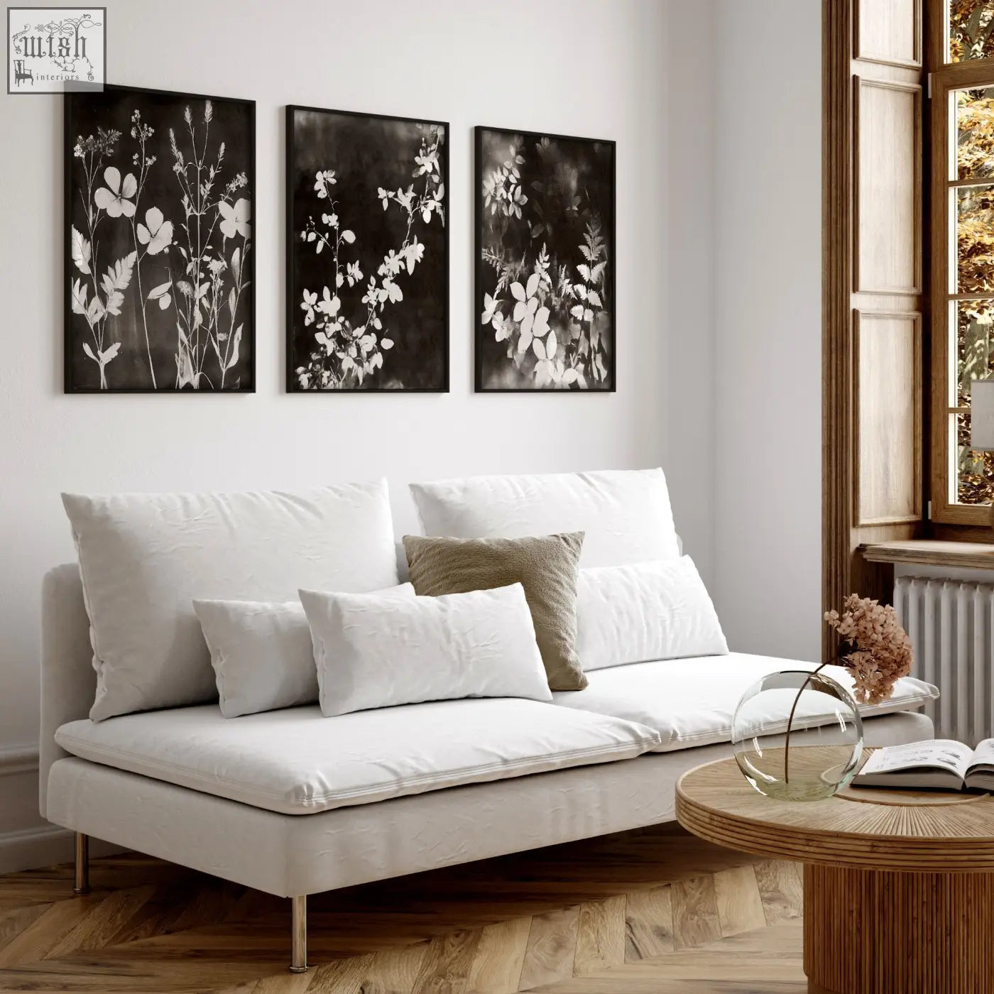 White upholstered sofa with metal legs and cushions in a living room featuring mink botanical dark floral wall art prints set of 3