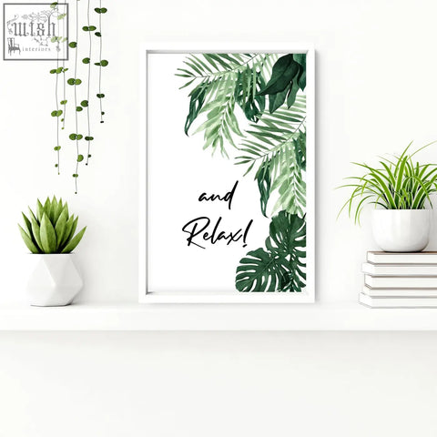White-framed wall art prints with green tropical leaves and black cursive text and relax for bathroom decor