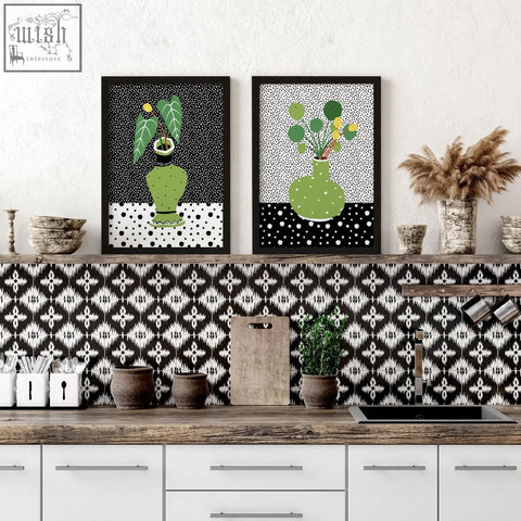 Two framed wall art poster prints featuring green vases with leafy plants in black frames on dotted background