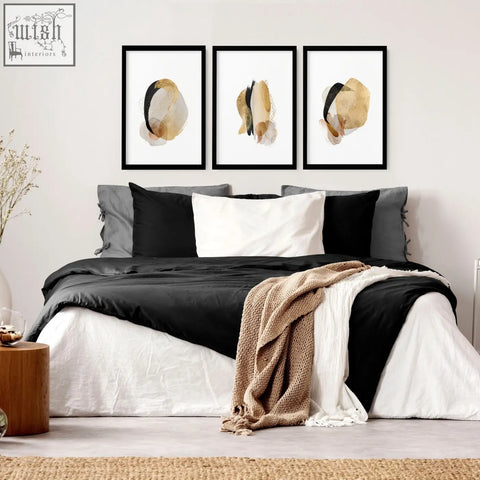 Three black-framed abstract art prints with beige and gold watercolor splashes for modern bedroom wall decor