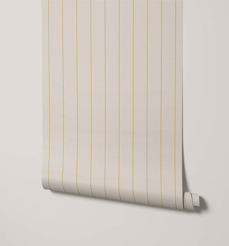 A roll of arthur minimal pinstripe wallpaper in off-white with delicate gold vertical stripes for a subtle look