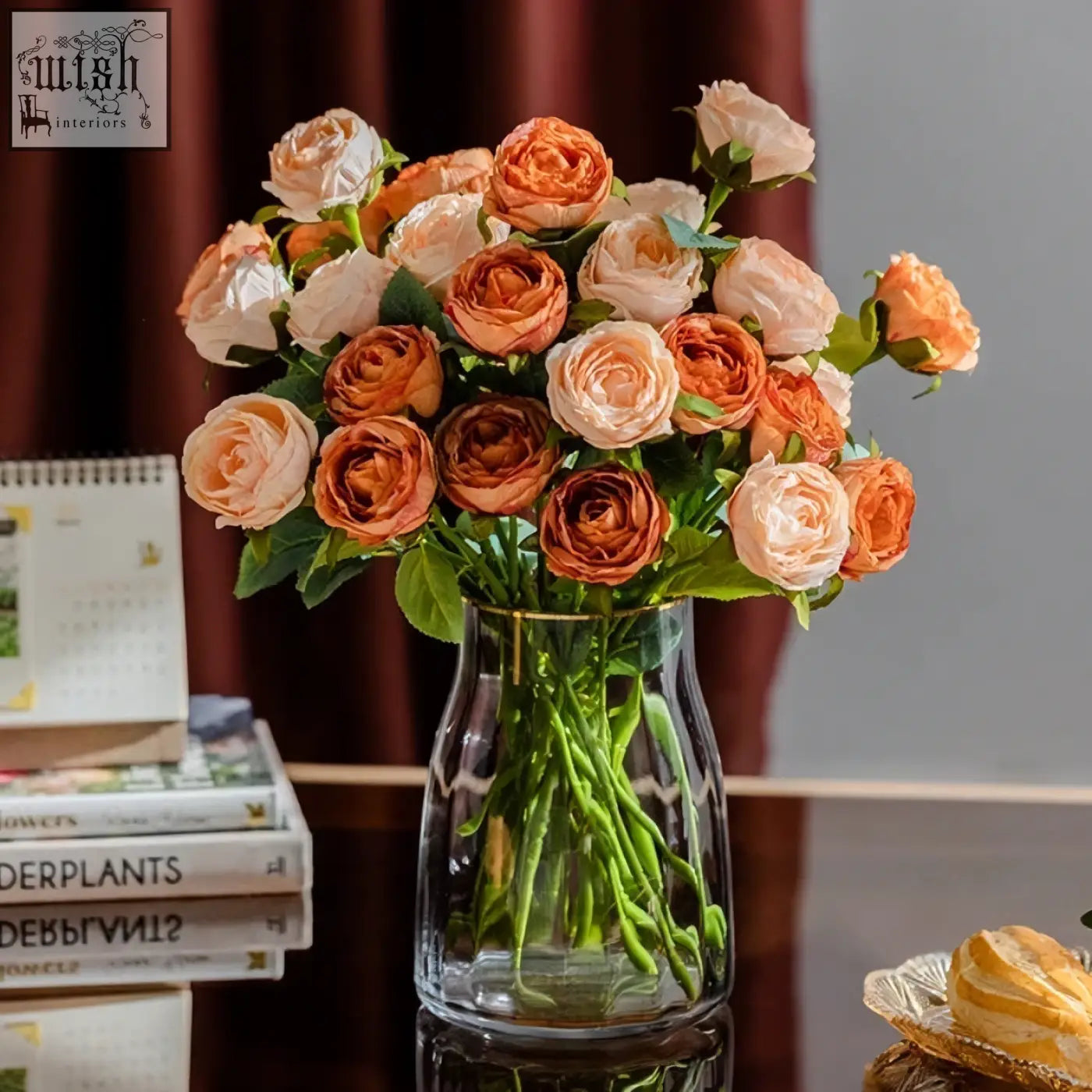 A clear glass vase with a gold rim holding peach and orange artificial roses for european entry lux rose living room decor