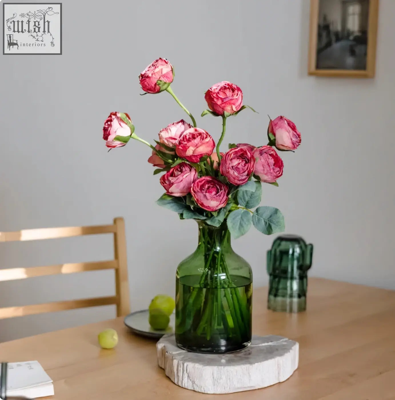 A green glass vase with artificial pink roses and lush leaves perfect for european entry lux rose living room decor