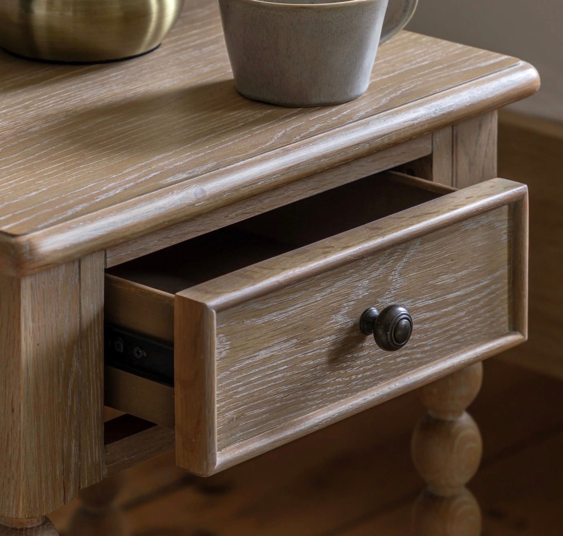Artisan bedside drawer in light gray distressed wood with single drawer and turned wooden legs for bedroom use