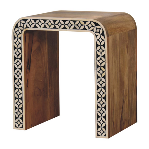 A sleek curved solid mango wood end table with rich brown finish and black and white floral bone inlay border