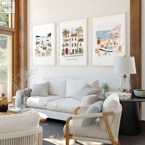 Three framed mediterranean coastal illustrations titled sotto il sole di amalfi hang above a white living room sofa