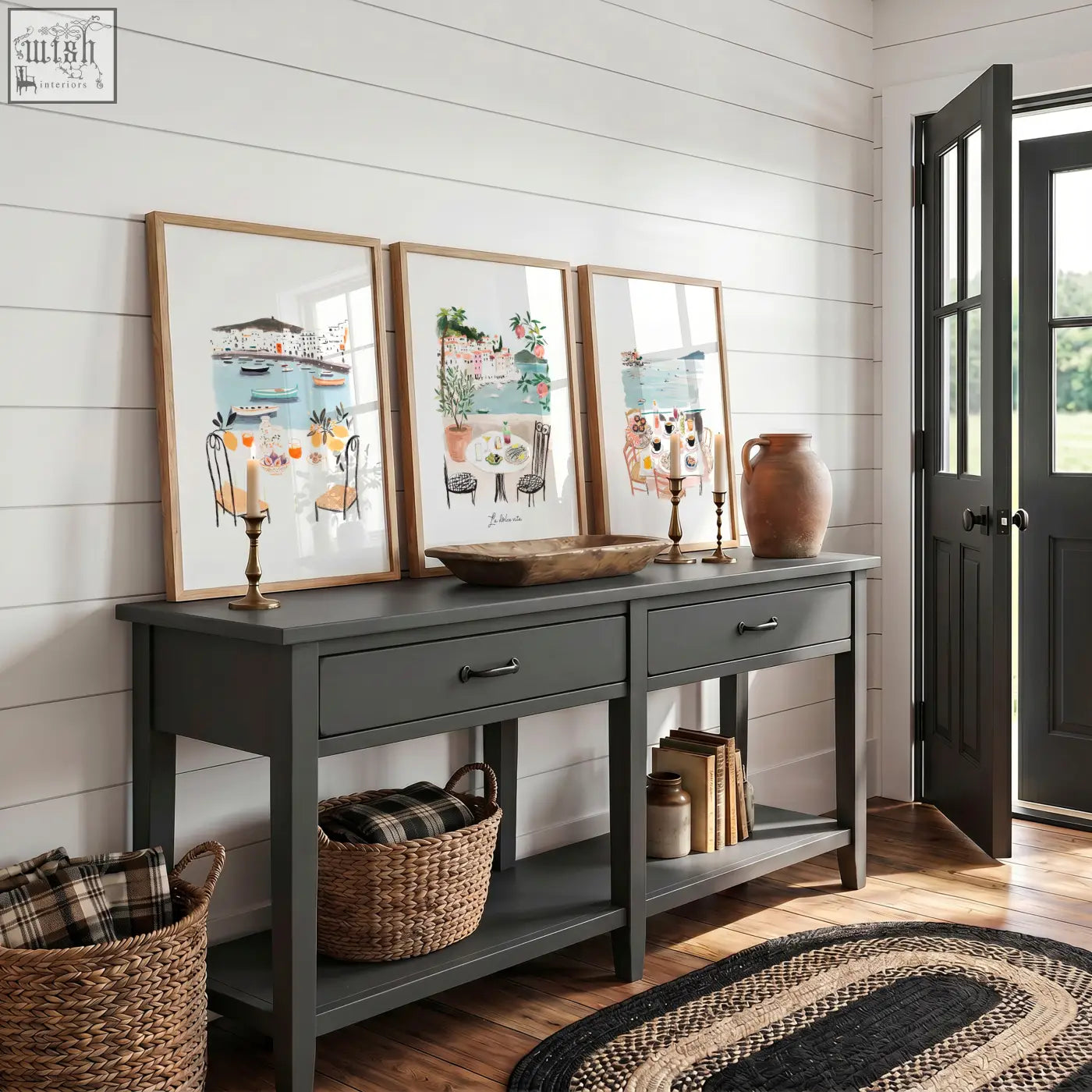 Dark gray console table with rustic wooden top black metal handles and open shelving shown with mediterranean coastal wall art prints set of three