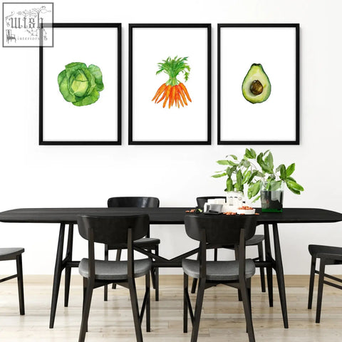 Three black-framed watercolor prints of green cabbage, orange carrots, and halved avocado for kitchen decor wall art