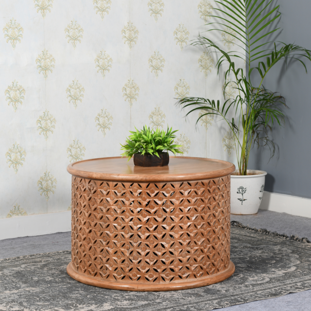 A round light brown artwork mango wood coffee table with geometric cutouts and a smooth top surface