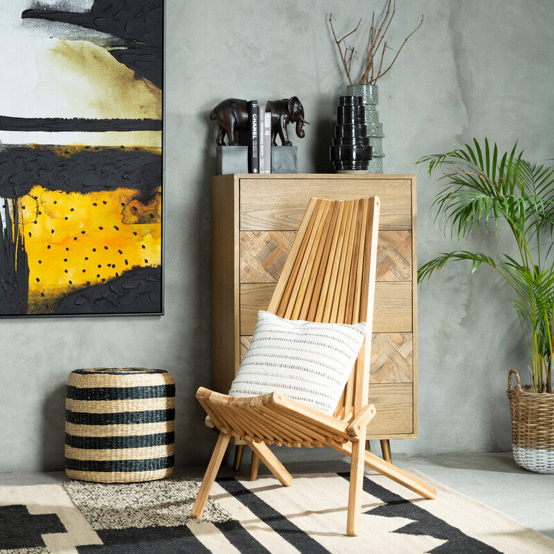 Light wood slat folding chair with a striped pillow next to ashby seagrass pouffe with black stripes and seagrass texture