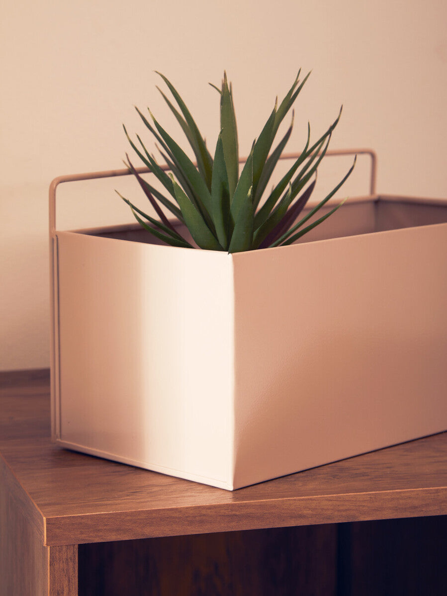 A sleek rose gold metal wall plant box with integrated handle holding a green succulent in a grey natural style