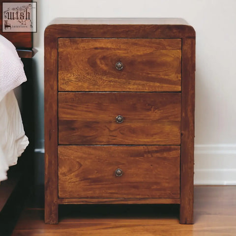 A warm chestnut solid mango wood nightstand with three drawers and round metal knobs perfect for bedroom use